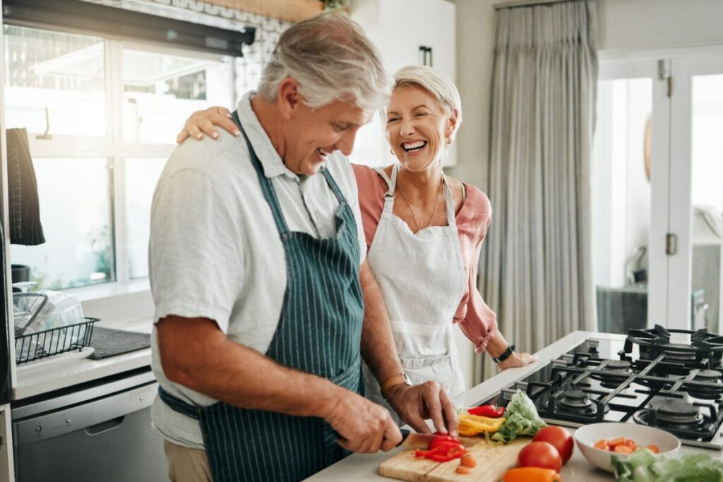 Smiling older couple cooking together in a bright kitchen at Garden Plaza senior living in Boise.